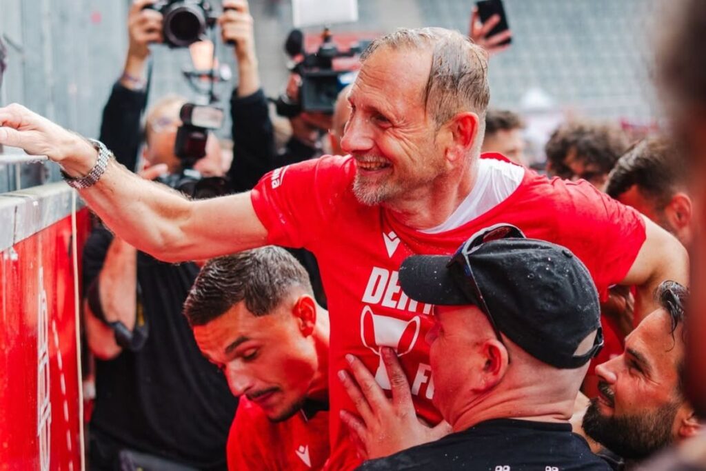 Head coach Mario Rustinelli with players, fans and security at Thun's title celebrations in the city.
